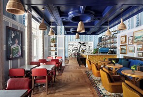 Un restaurante con pisos de madera, sillas rojas y una zona de bar con un sofá azul.