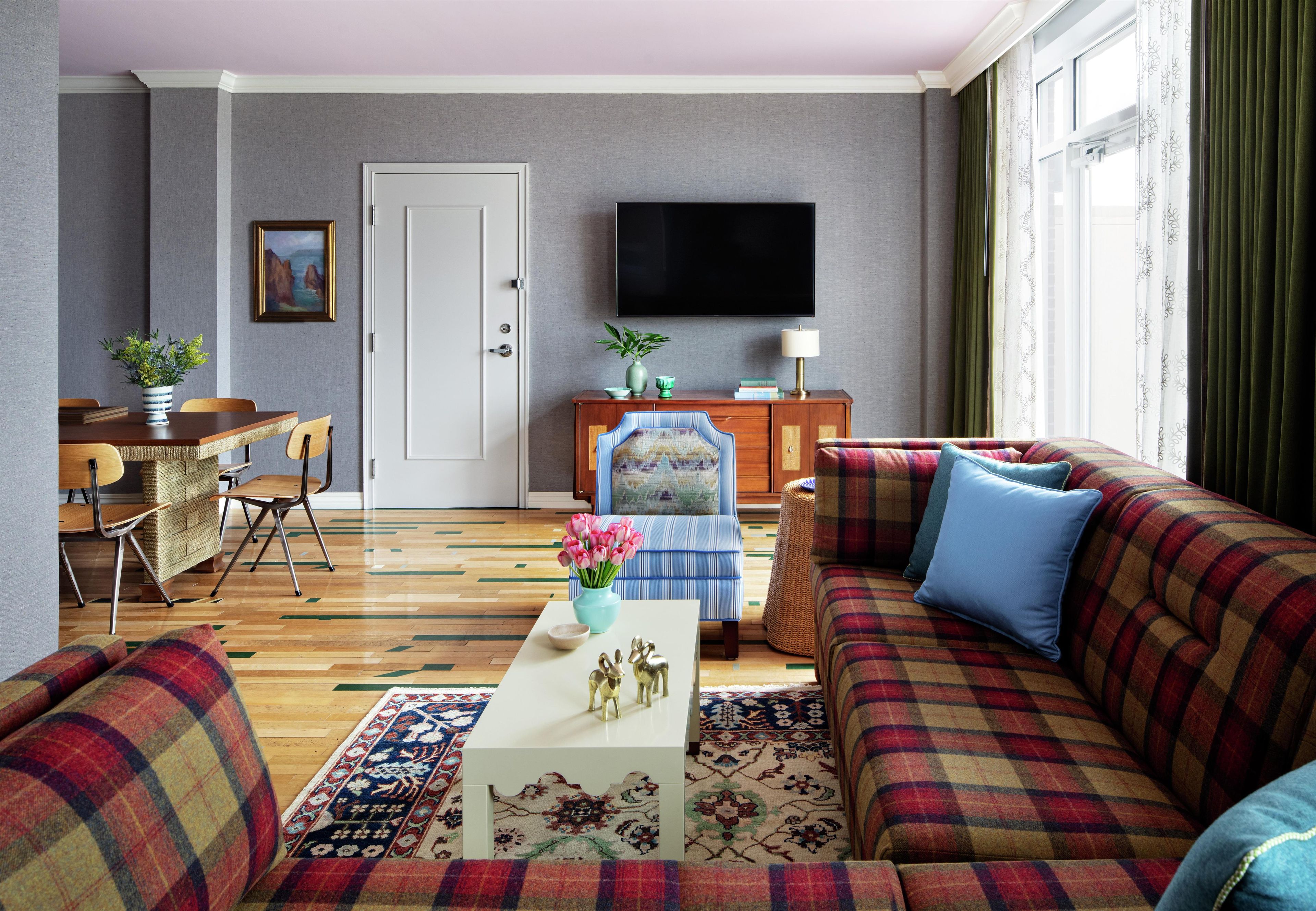 Un salon comprenant un canapé, un fauteuil, une table basse et un téléviseur à écran plat fixé au mur.