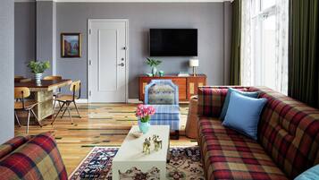 Un salon comprenant un canapé, un fauteuil, une table basse et un téléviseur à écran plat fixé au mur.