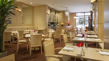 A restaurant with multiple tables and chairs, a large mirror, and a chandelier.