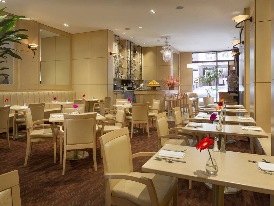 A restaurant with multiple tables and chairs, a large mirror, and a chandelier.
