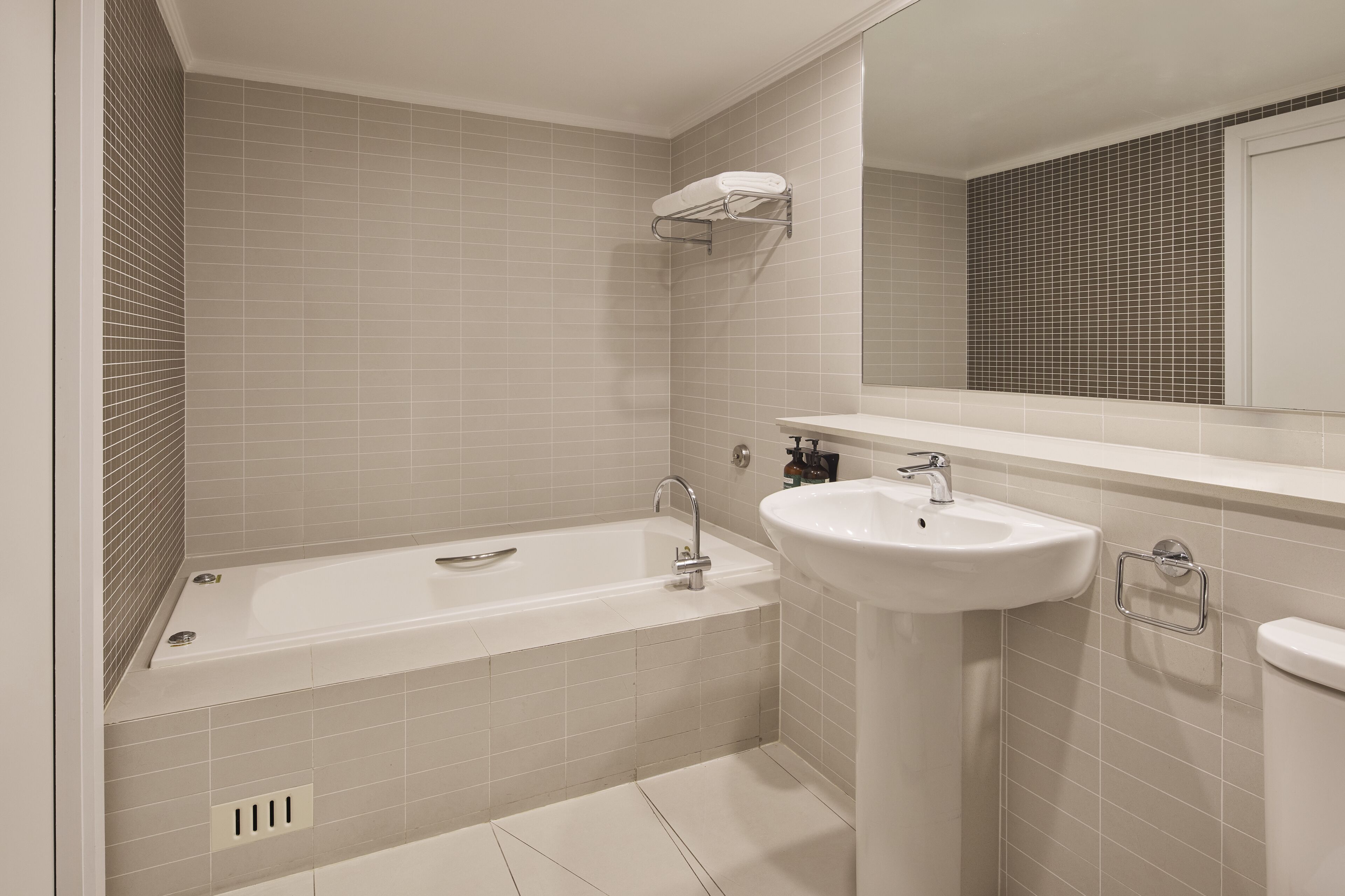 A modern bathroom with a bathtub, a sink, and a mirror.