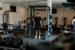 Un gimnasio con equipo de levantamiento de pesas, cintas de correr y bicicletas estáticas.