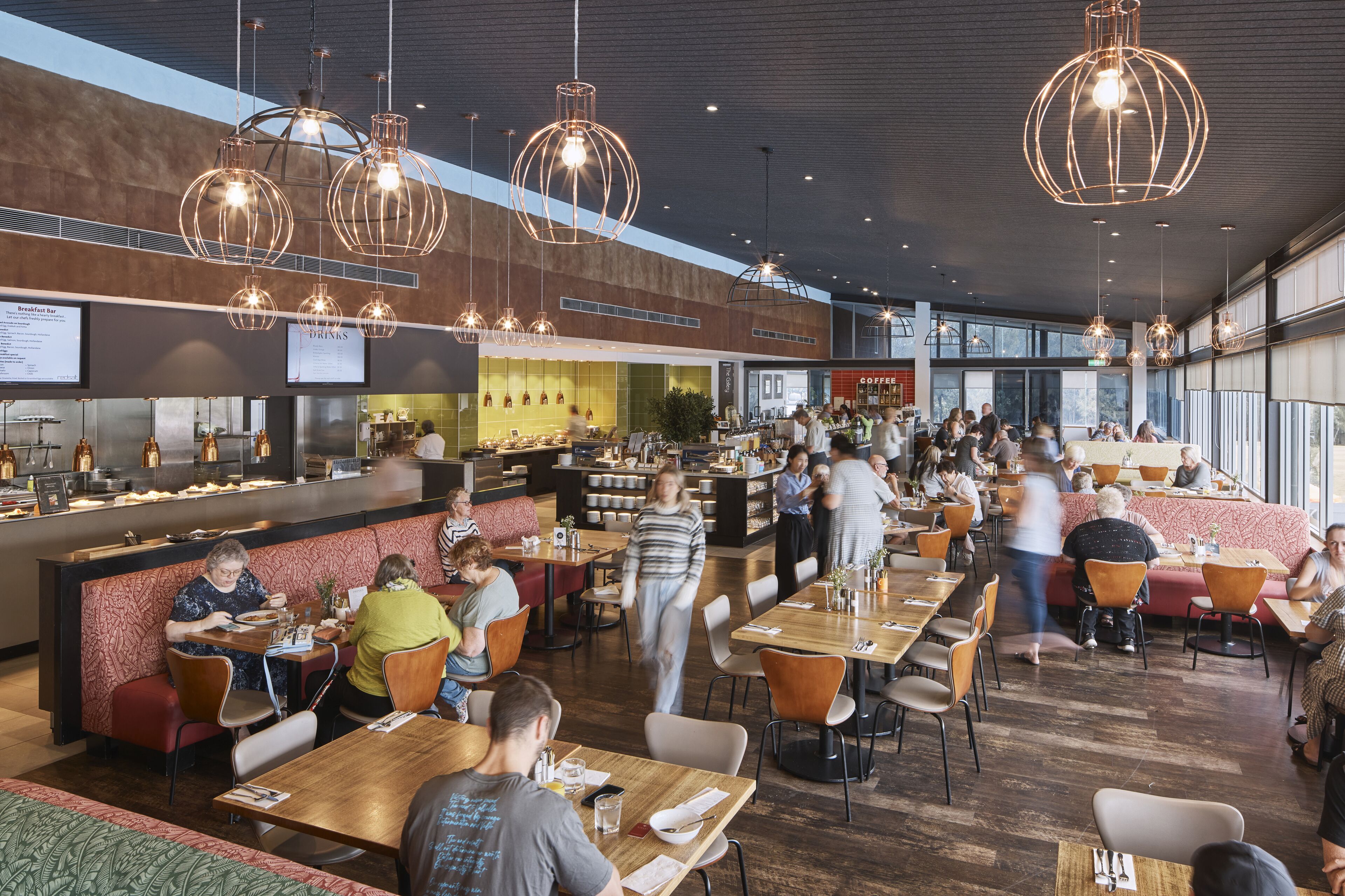 A spacious restaurant with multiple dining areas, a bar, and a counter with a menu.