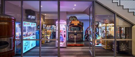 Ein hell erleuchteter Arcade-Bereich mit verschiedenen Spielautomaten, darunter ein 'Jurassic Park'-Spiel.
