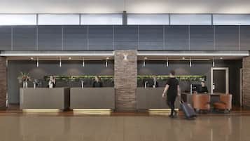 A modern reception area with a stone pillar, reception desks, and a seating area with leather chairs.