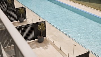 A modern pool area with a clear blue pool, potted plants, and a tiled deck.