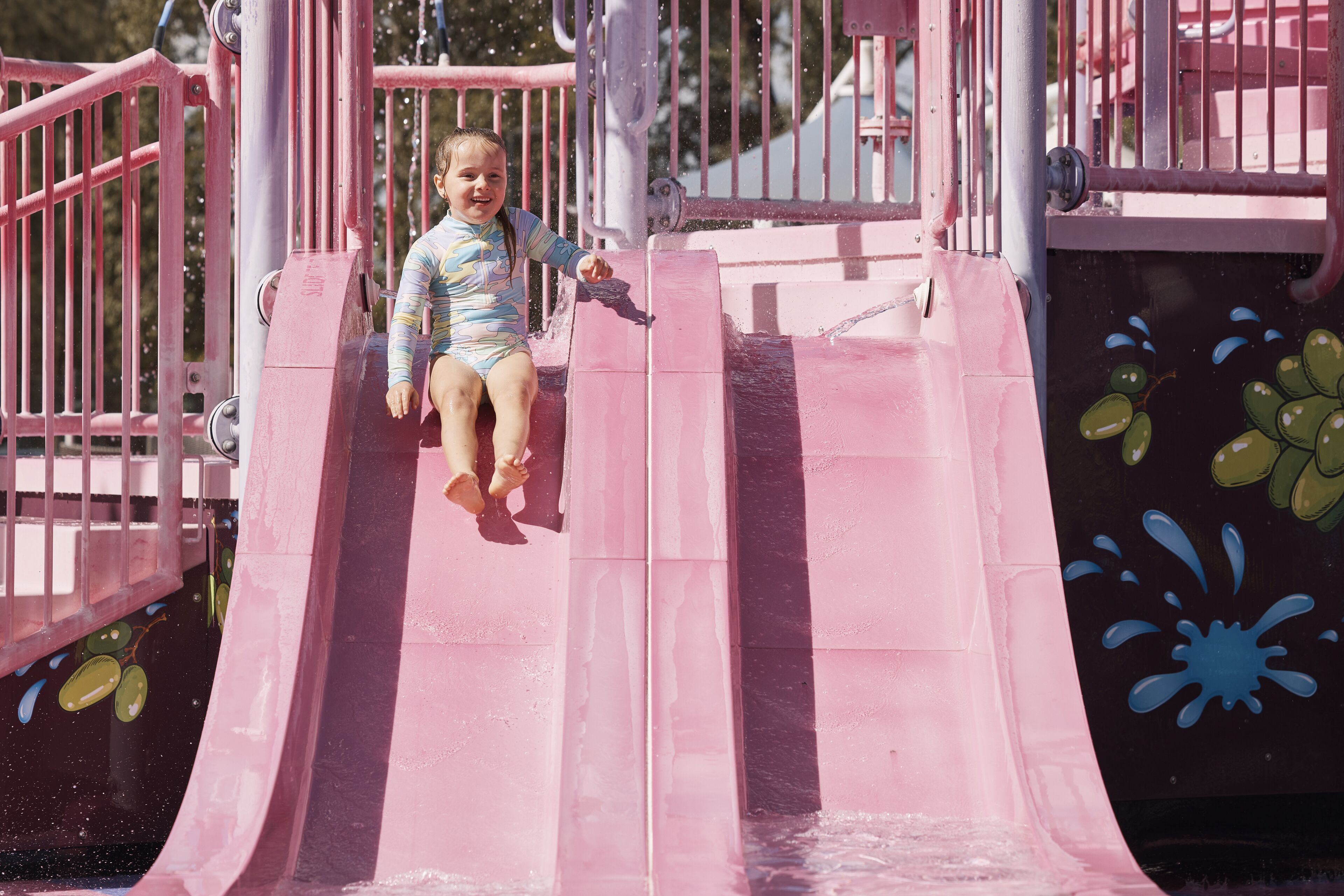 A child on a pink slide at a playground.