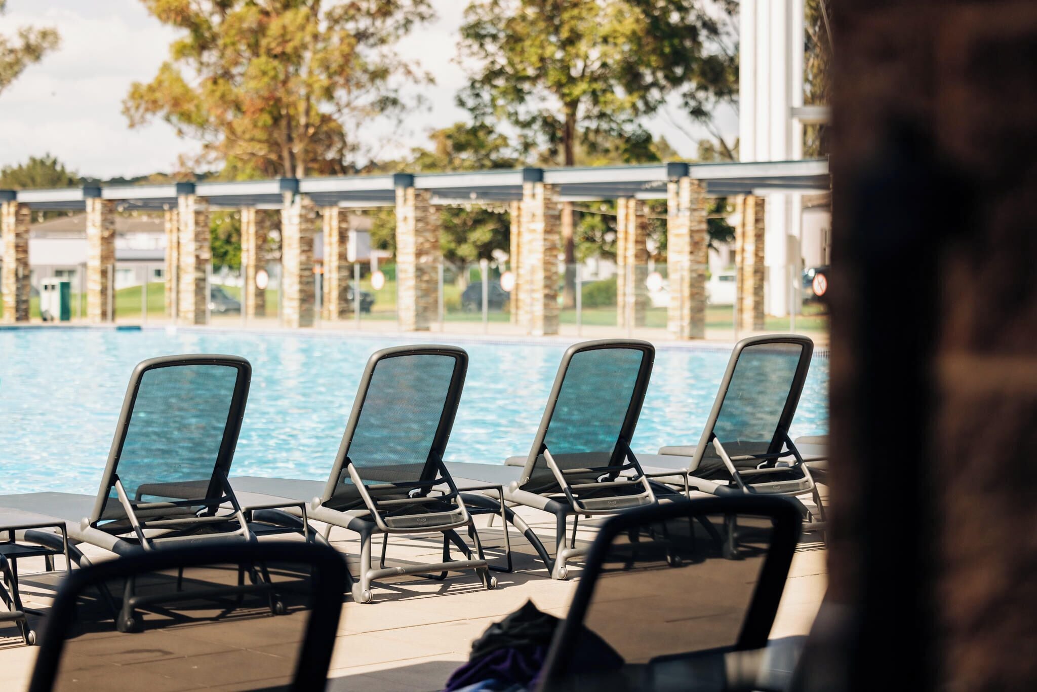 Un área junto a la piscina con sillones de descanso y vista al agua.
