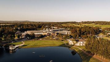 Vista aerea di un campo da golf con un club house, un edificio importante e un lago.