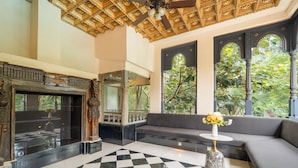 A lobby with a checkered floor, a sofa, a small table with a vase, and a ceiling fan.