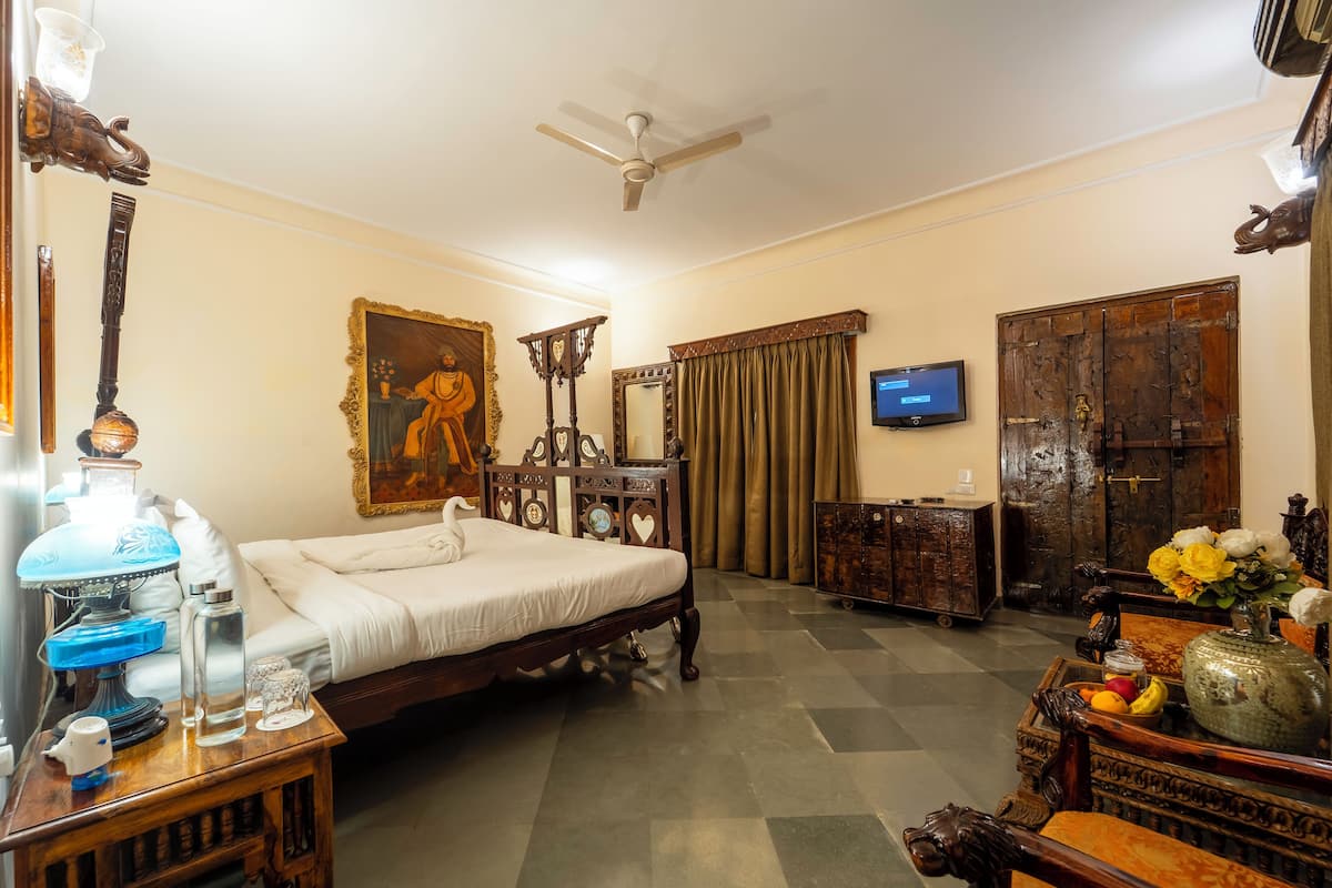 Una habitación tradicional con cama, ventilador de techo, televisión y armario de madera.