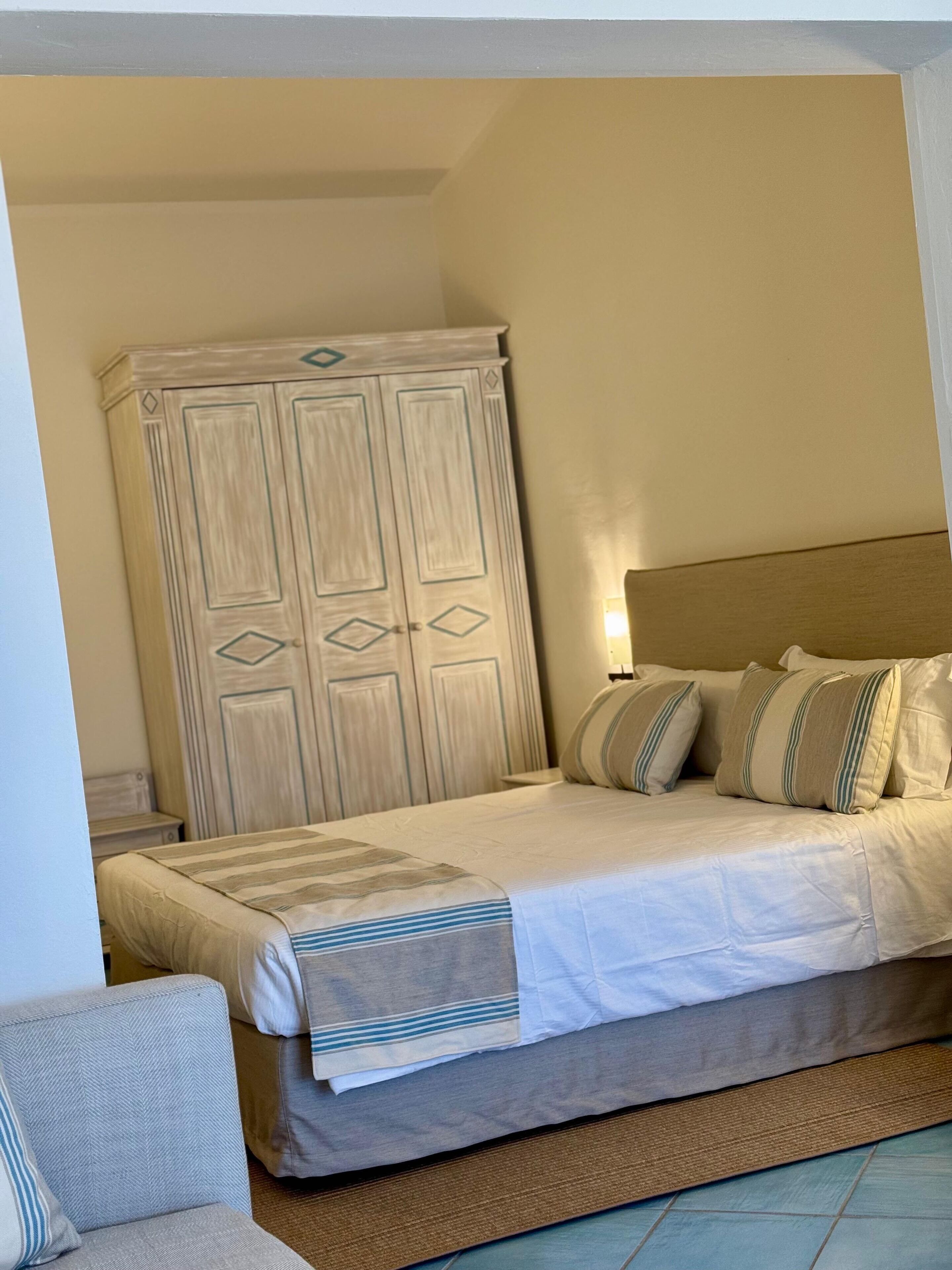 A bedroom with a bed, pillows, a nightstand, and a wardrobe.