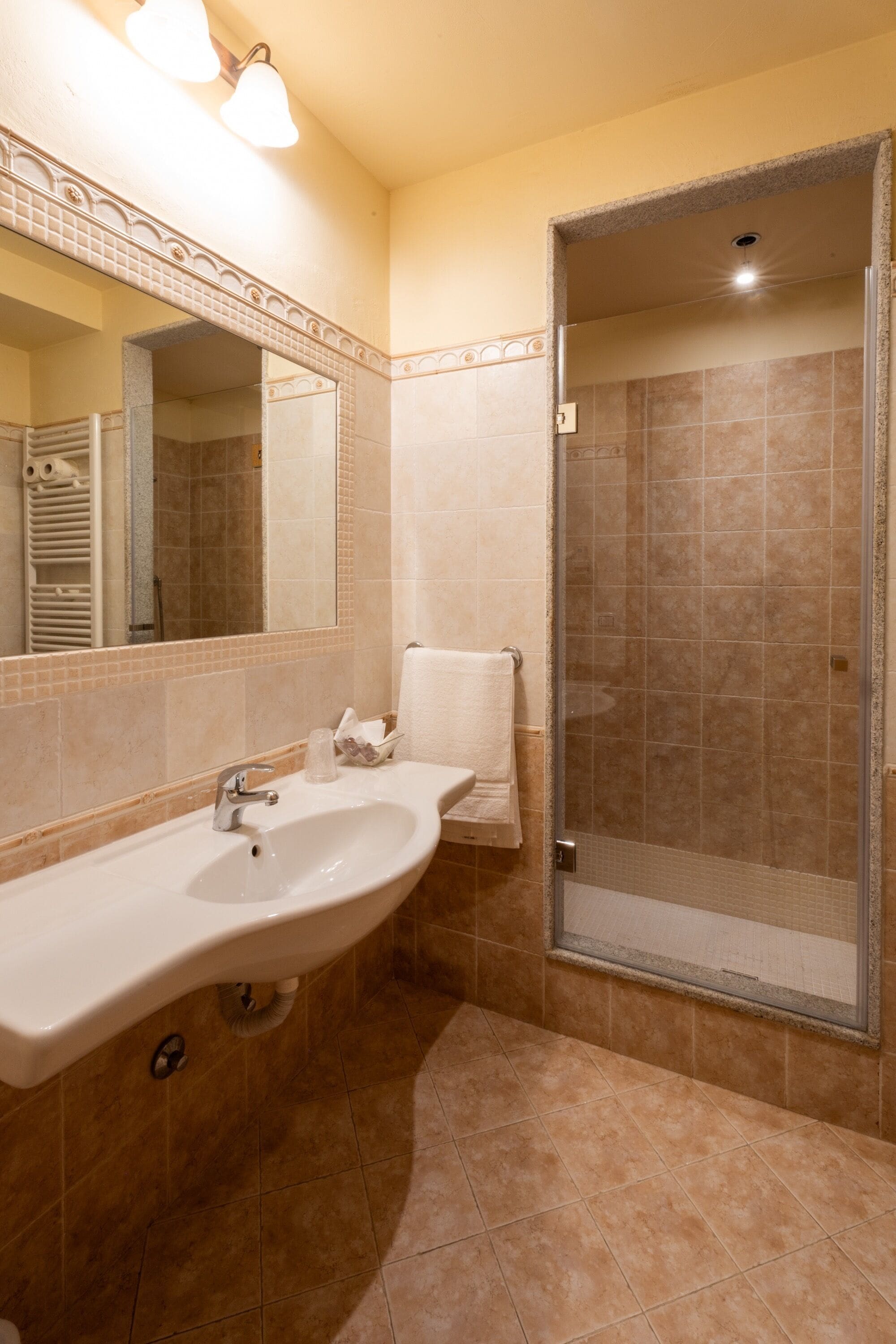 A bathroom with a sink, mirror, and shower area.