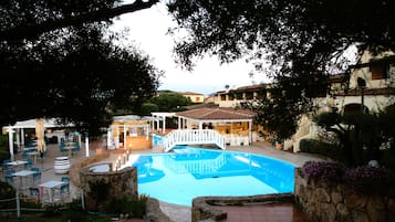 Relax by the serene pool surrounded by lush greenery and Mediterranean-style architecture.