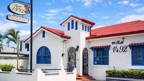 A white building with red roofs and blue windows, marked as Hotel 1492. - Hotel 1492 (San José)