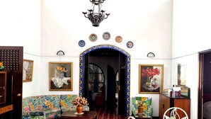 A room with a patterned floor, a sofa, a table with chairs, and a doorway leading to another room. - Hotel 1492 (San José)