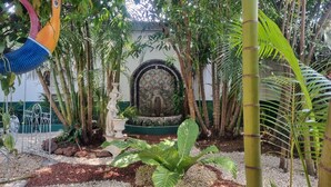 A garden with a fountain, a statue, and a decorative wall. - Hotel 1492 (San José)
