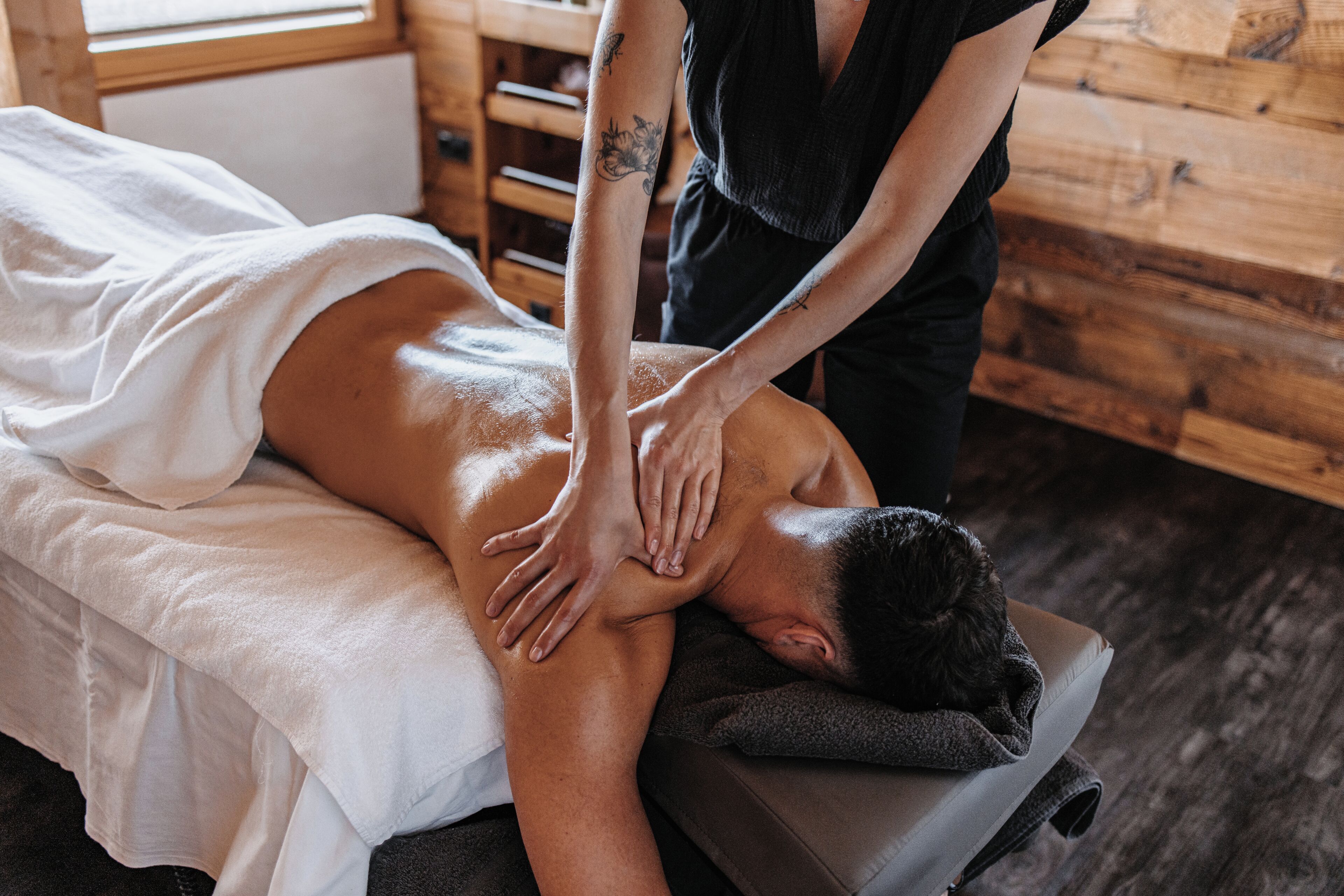 A massage therapy session in a room with wooden walls and a massage table.