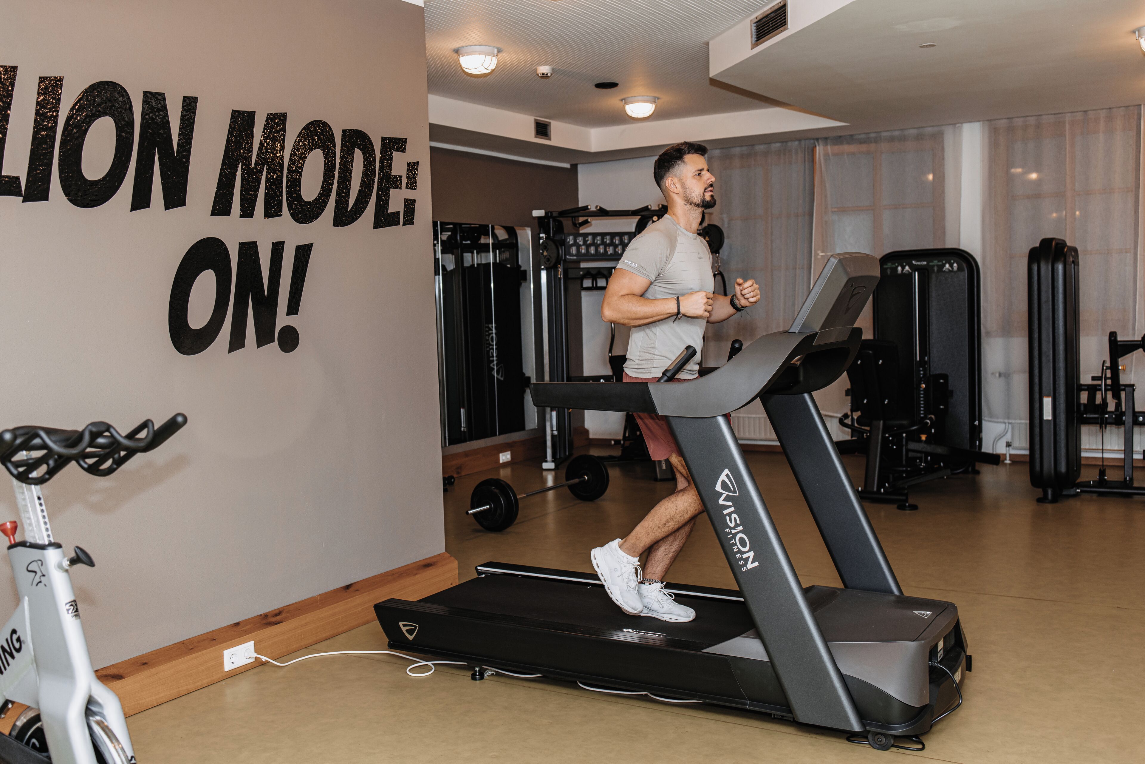 A gym with a treadmill, weight machines, and a wall with motivational text.