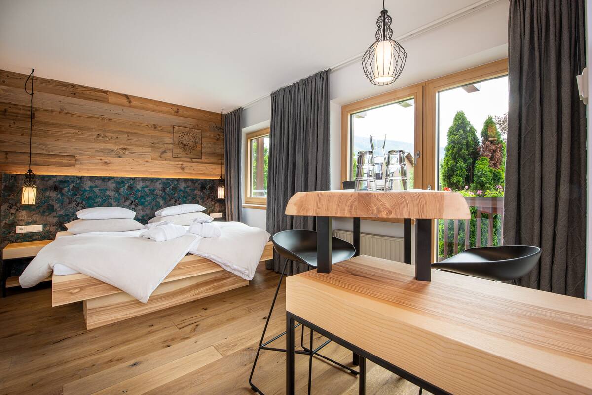 Ein modernes Schlafzimmer mit einem Holzbett, einem Esstisch und Blick ins Freie.