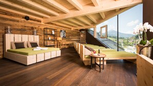 Una cabaña de madera con dos camas, una mesita y vistas a la montaña.