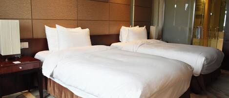 Et hotelværelse med to senge, et natbord, en lampe og et billede på væggen.