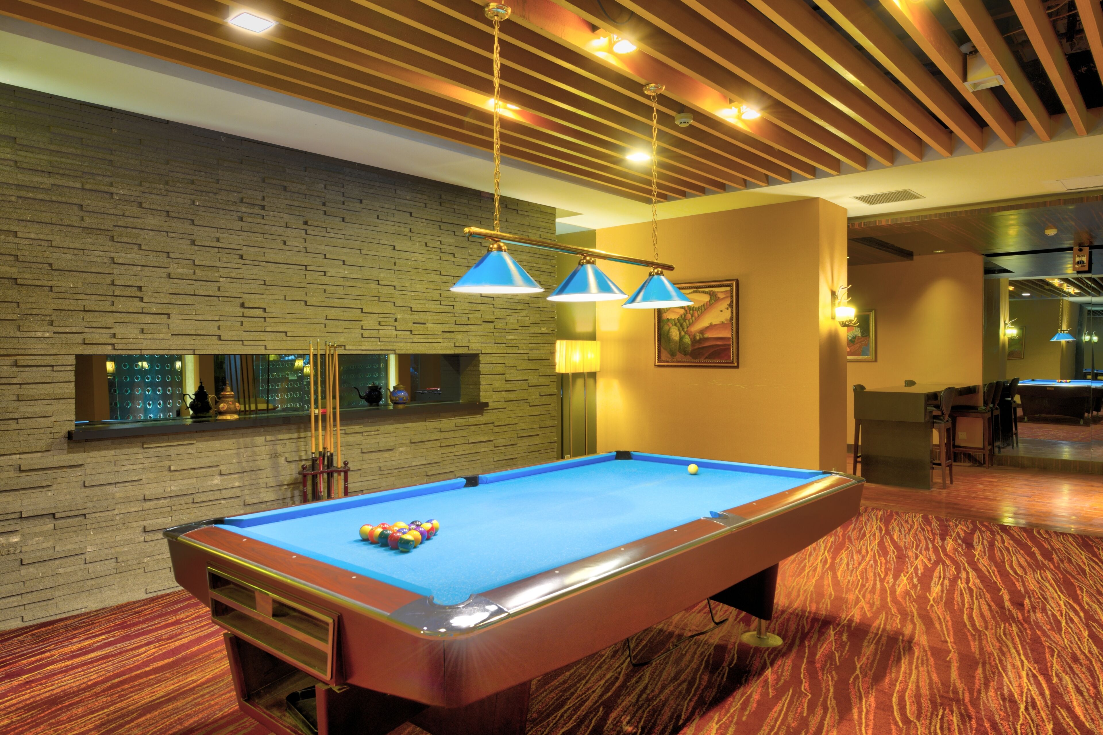 A pool table with balls, a billiard rack, and a wall with a brick pattern.