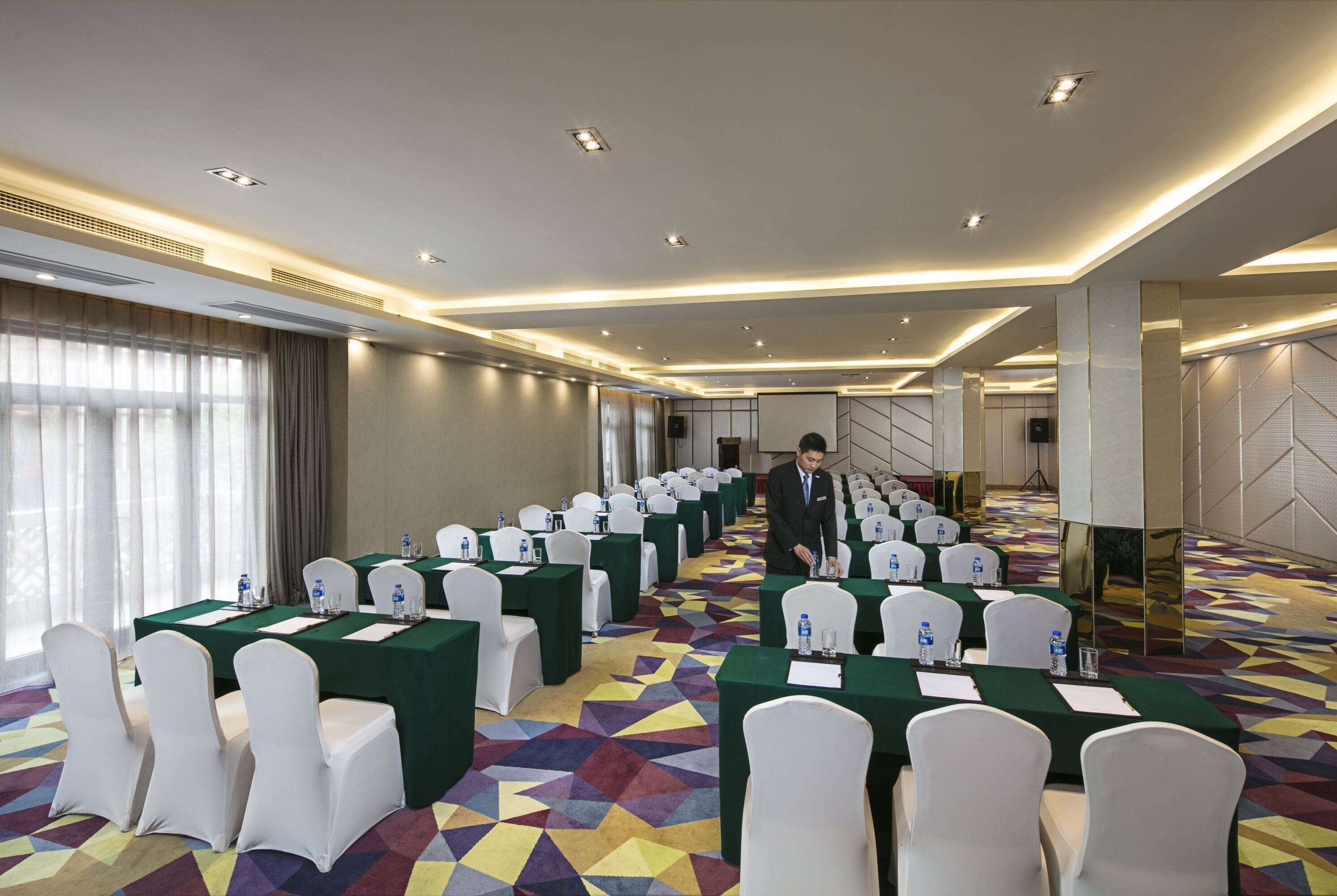 A conference room with multiple tables, chairs, and a carpeted floor.