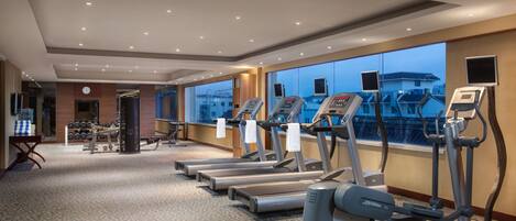 A hotel fitness center with treadmills, weight machines, and a mirrored wall.