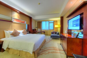 Habitación de hotel con una cama grande, un escritorio, televisor y zona de estar.