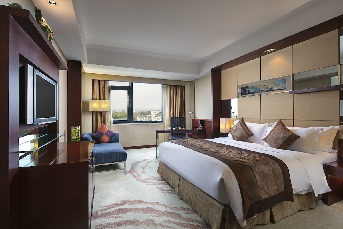 Une chambre d’hôtel avec un grand lit, un bureau, une télévision et une vue sur la ville.