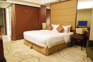 Una habitación de hotel con una cama grande, un escritorio con una computadora y un televisor.