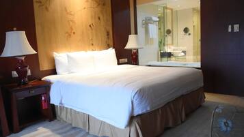A hotel room with a large bed, two bedside lamps, a nightstand, a mirror, and a carpeted floor.