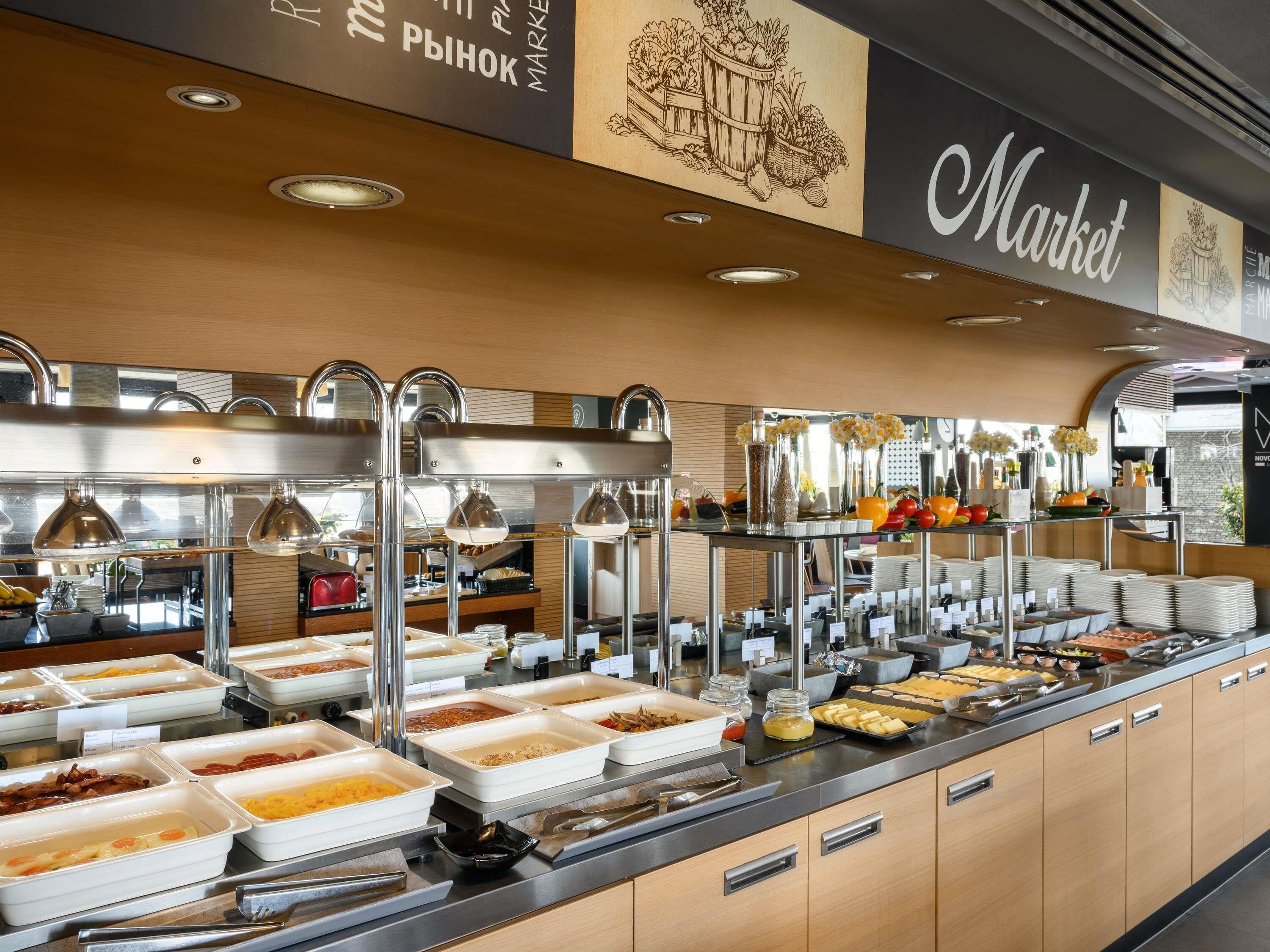 Un buffet avec différents stands de nourriture, un éclairage suspendu et une pancarte indiquant « Marché ».