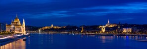 A nighttime cityscape with illuminated buildings and a river. - Novotel Budapest Danube (Budapest)