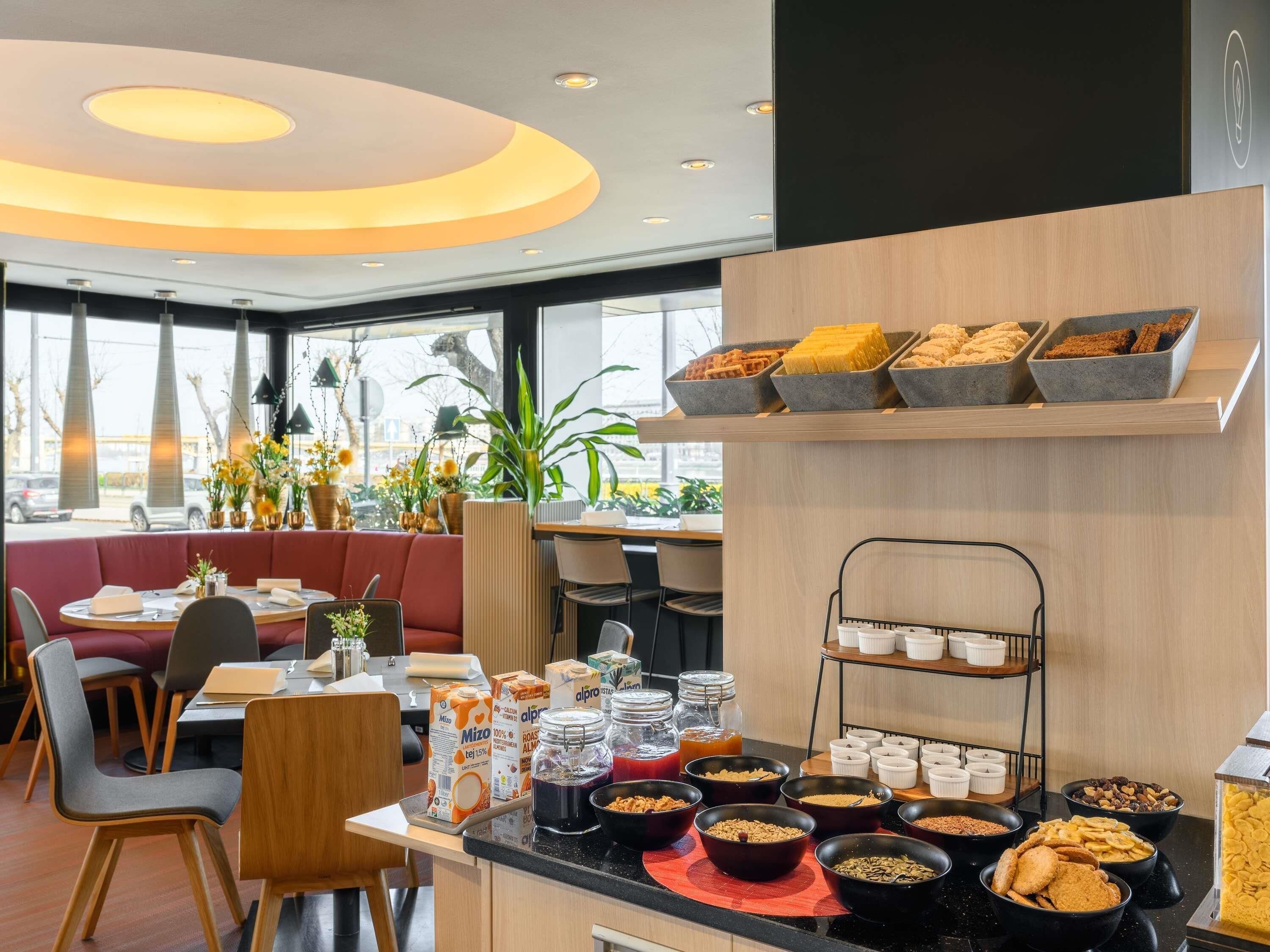 A breakfast buffet with various food items and a seating area with a red cushioned bench.