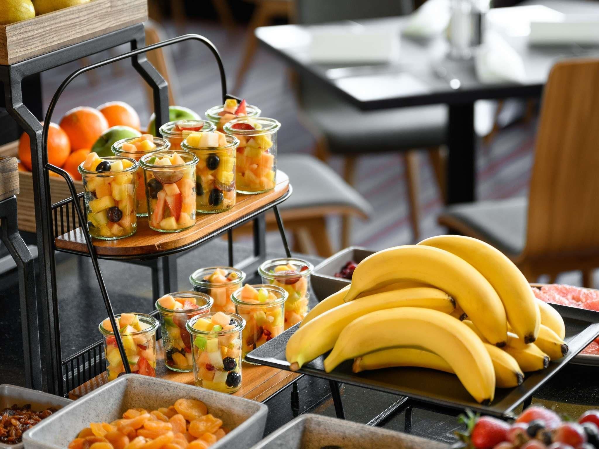 A buffet with fruit cups, bananas, and dried fruits.