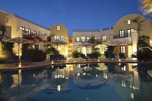 Un hotel con piscina, sillones de descanso y sombrillas.