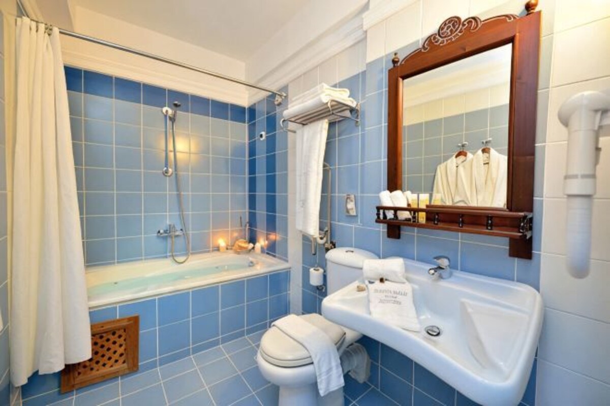 Un baño con bañera, inodoro, lavabo y espejo.
