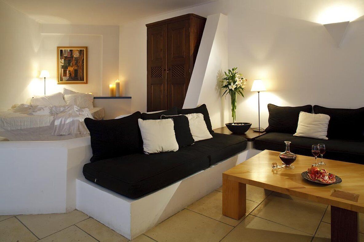 A modern living room with a black and white sofa, a wooden coffee table with a plate of food and glasses, and a painting on the wall.