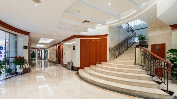 A spacious lobby with a curved staircase, a polished marble floor, and a modern ceiling design. - New Era Hotel (Nanjing)