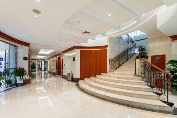 Un hall d’entrée spacieux, doté d’un escalier à volutes, d’un sol en marbre poli et d’un design de plafond moderne.