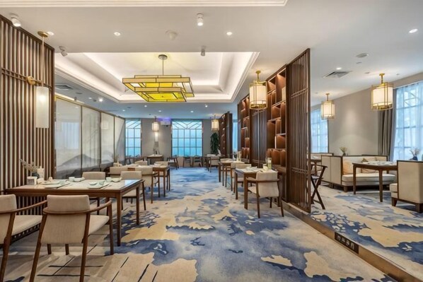 A hotel lobby with multiple seating areas, a patterned carpet, and a large chandelier. - New Era Hotel (Nanjing)