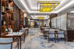 A hotel lobby with a central seating area, wooden bookshelves, and a patterned carpet. - New Era Hotel (Nanjing)