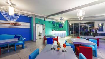 Un restaurante moderno con asientos azules y rojos, una pared de acento color turquesa y un área de recepción.