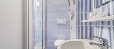 Un bagno con doccia, WC e lavandino.