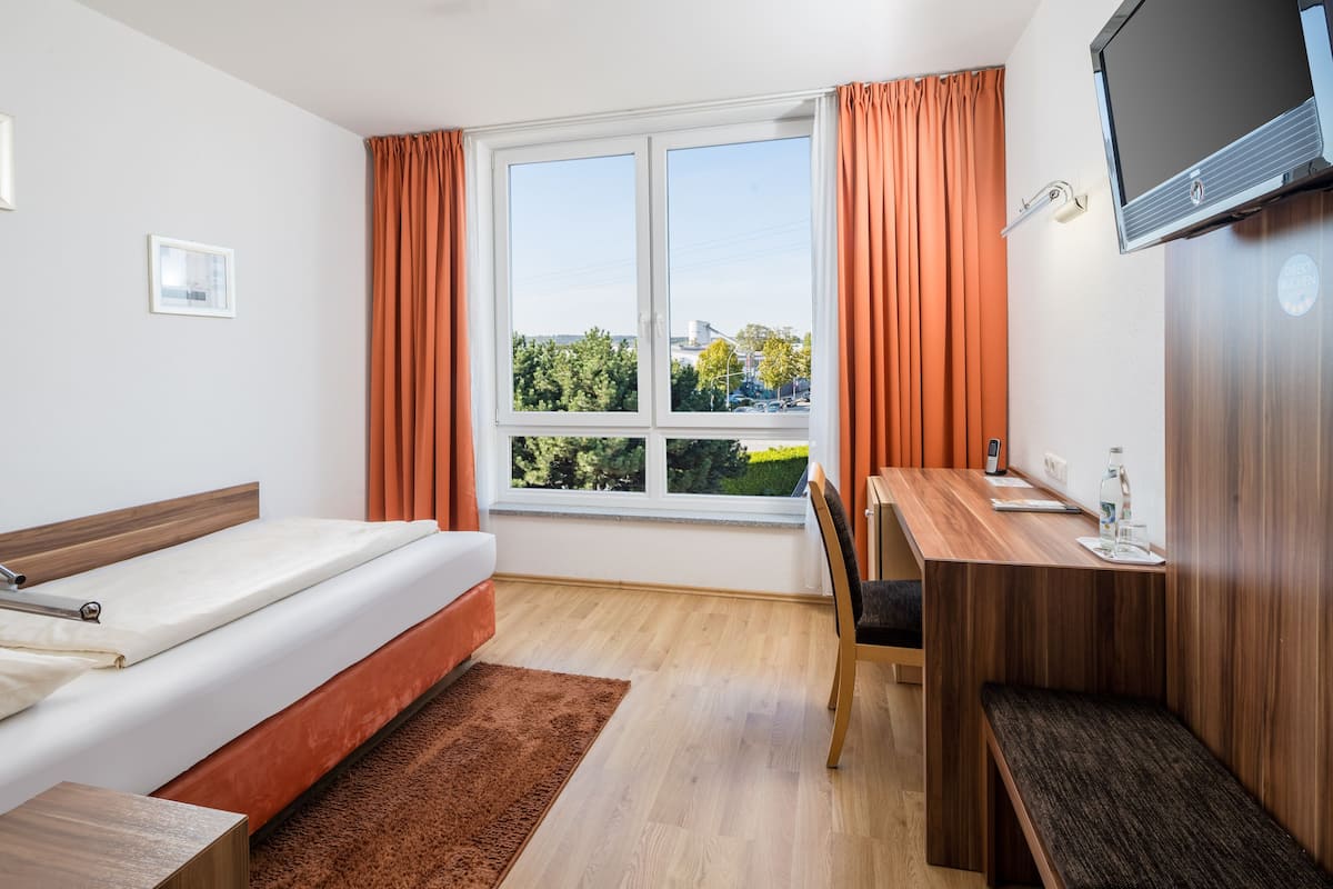 A modern hotel room with a bed, a desk, and a TV.