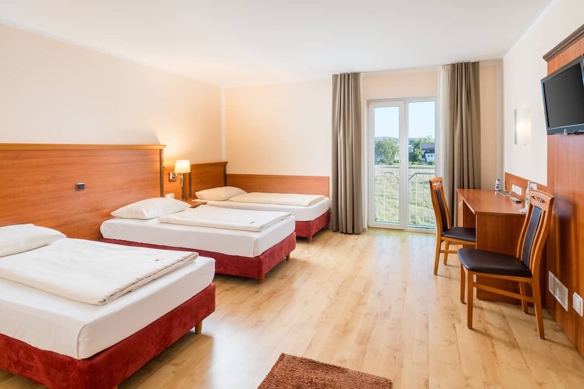 A hotel room with two beds, a desk, and a chair.
