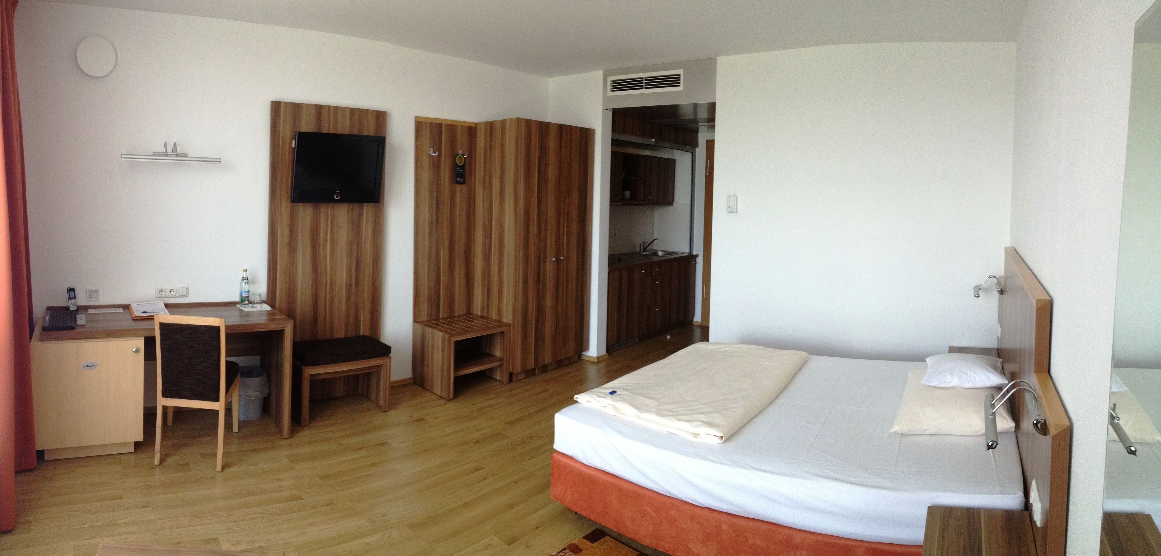 A bedroom with a bed, a desk, a chair, a wardrobe, and a bathroom.